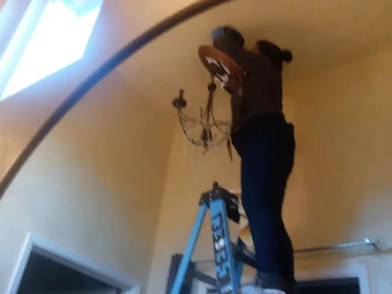 Electrician installing a chandelier in a Addis residence